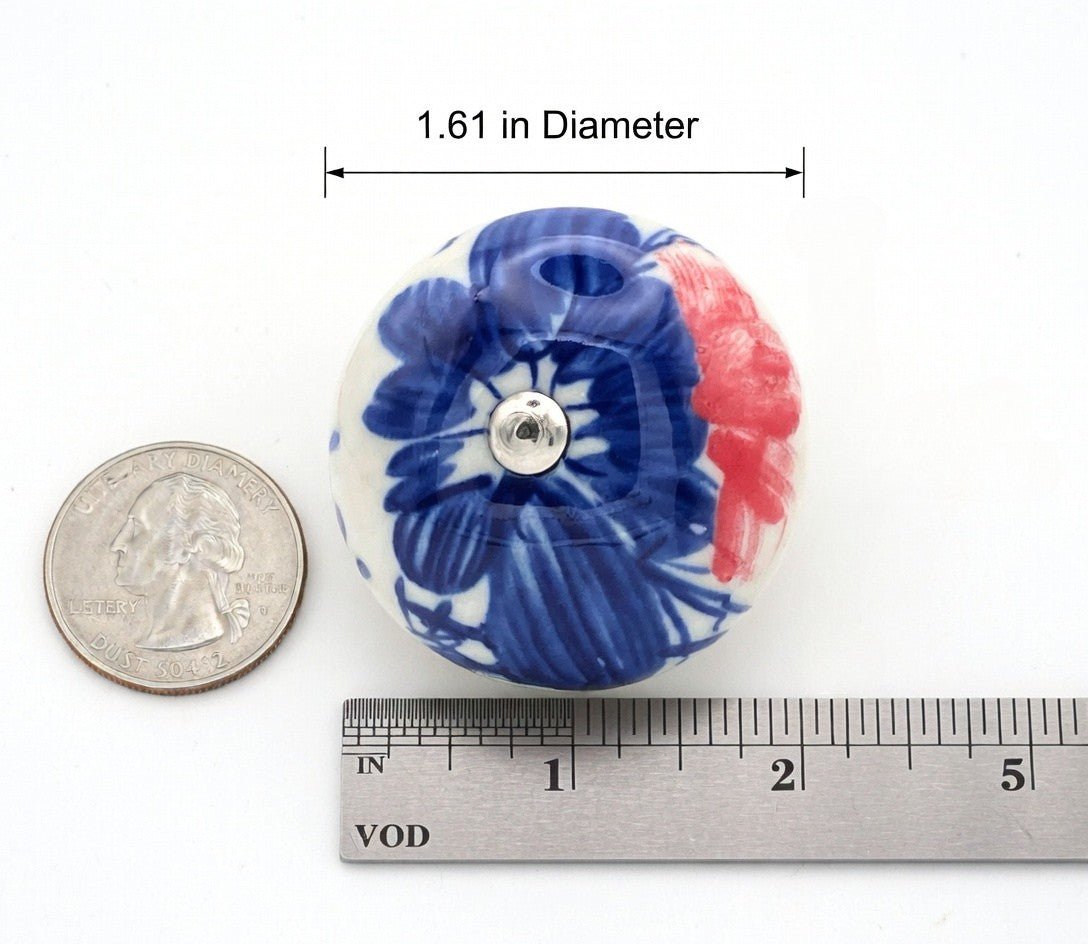 Decorative knob with floral design next to a ruler and quarter for scale on a white background