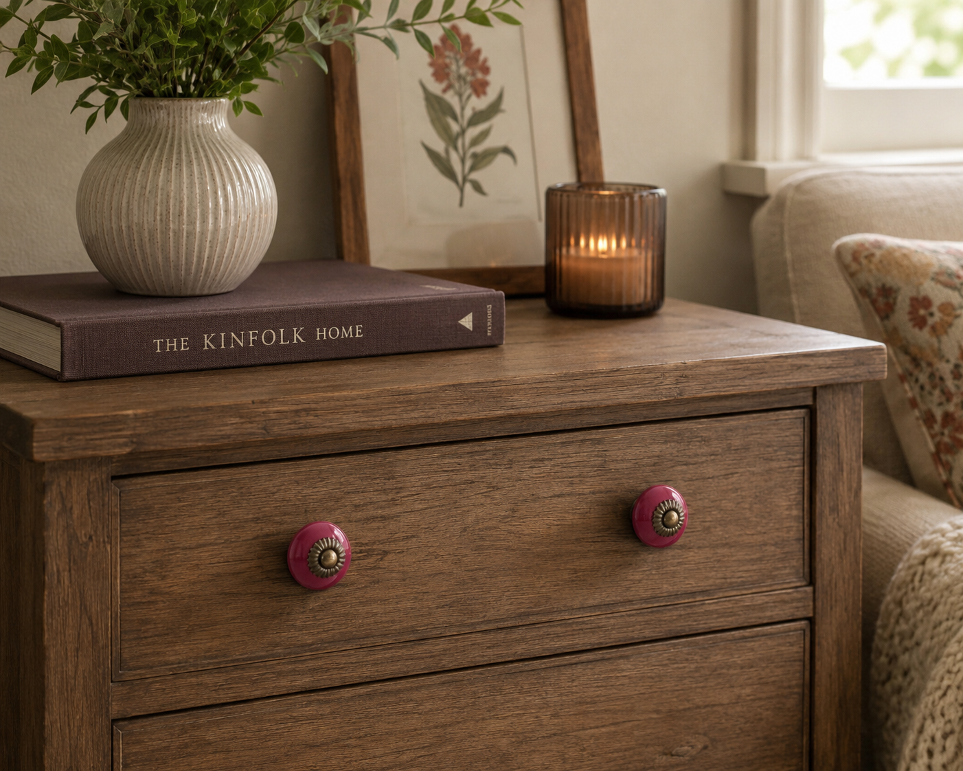 Red ceramic drawer knobs featured on a vintage nightstand styled in a cozy bedroom setting.