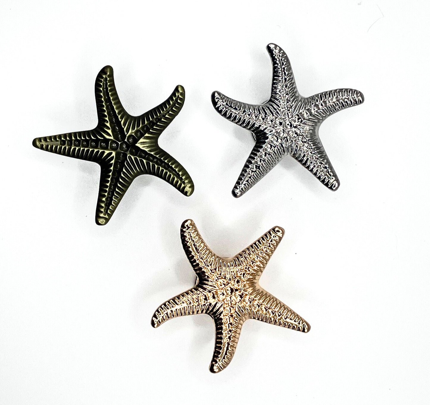 Three starfish-shaped objects in gold, silver, and bronze on a white background