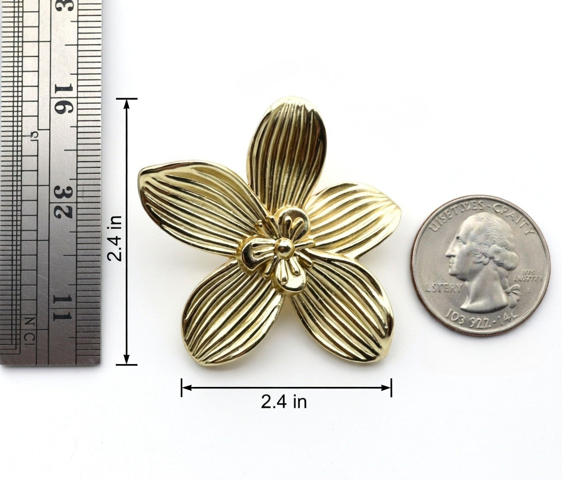 Gold flower-shaped knob with measurements and a quarter for scale on a white background