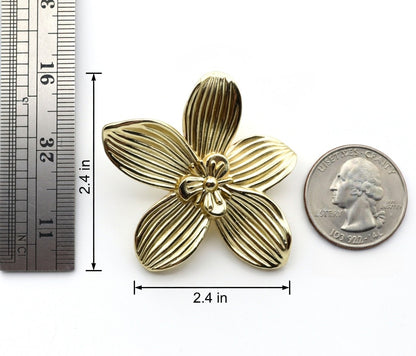 Gold flower-shaped knob with measurements and a quarter for scale on a white background