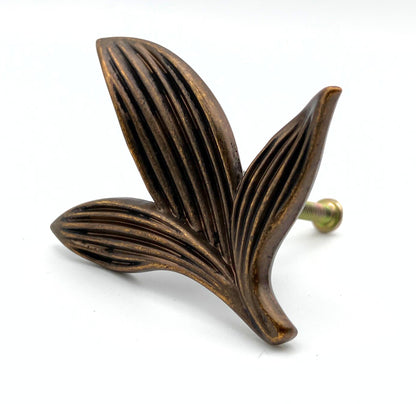 Decorative leaf-shaped brass knob on a white background