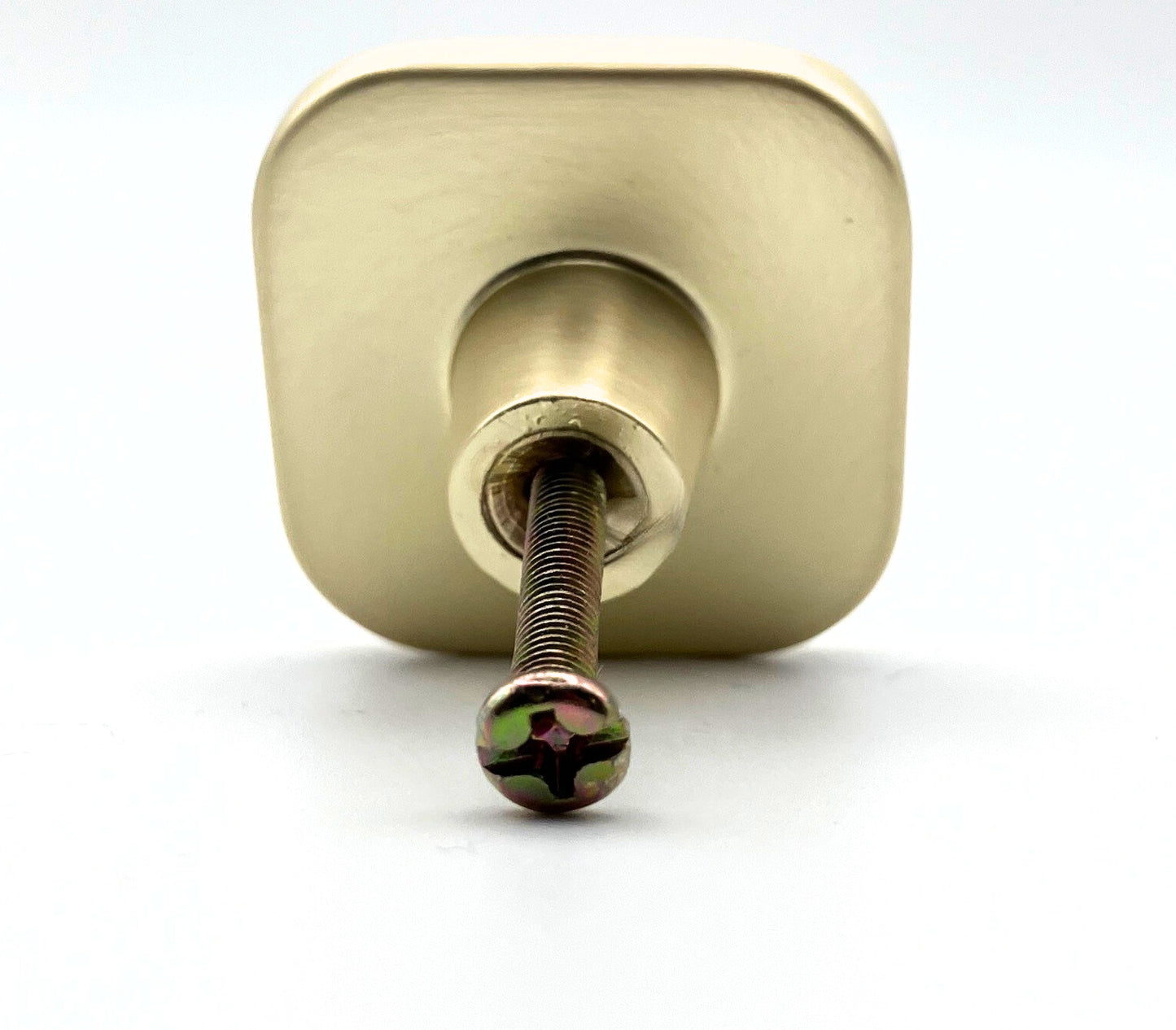 Square with rounded corners shaped knob with off-white inset and brass gold metal trim
