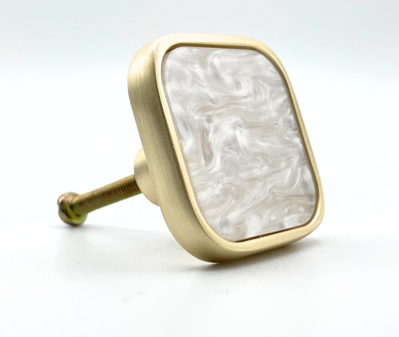 Decorative knob with gold frame and white marble pattern on a white background