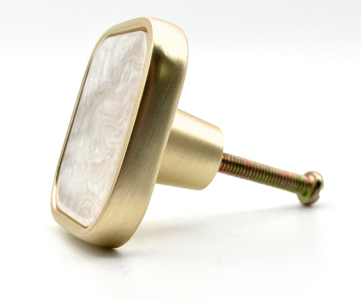Brass cabinet knob with a white marble center on a white background