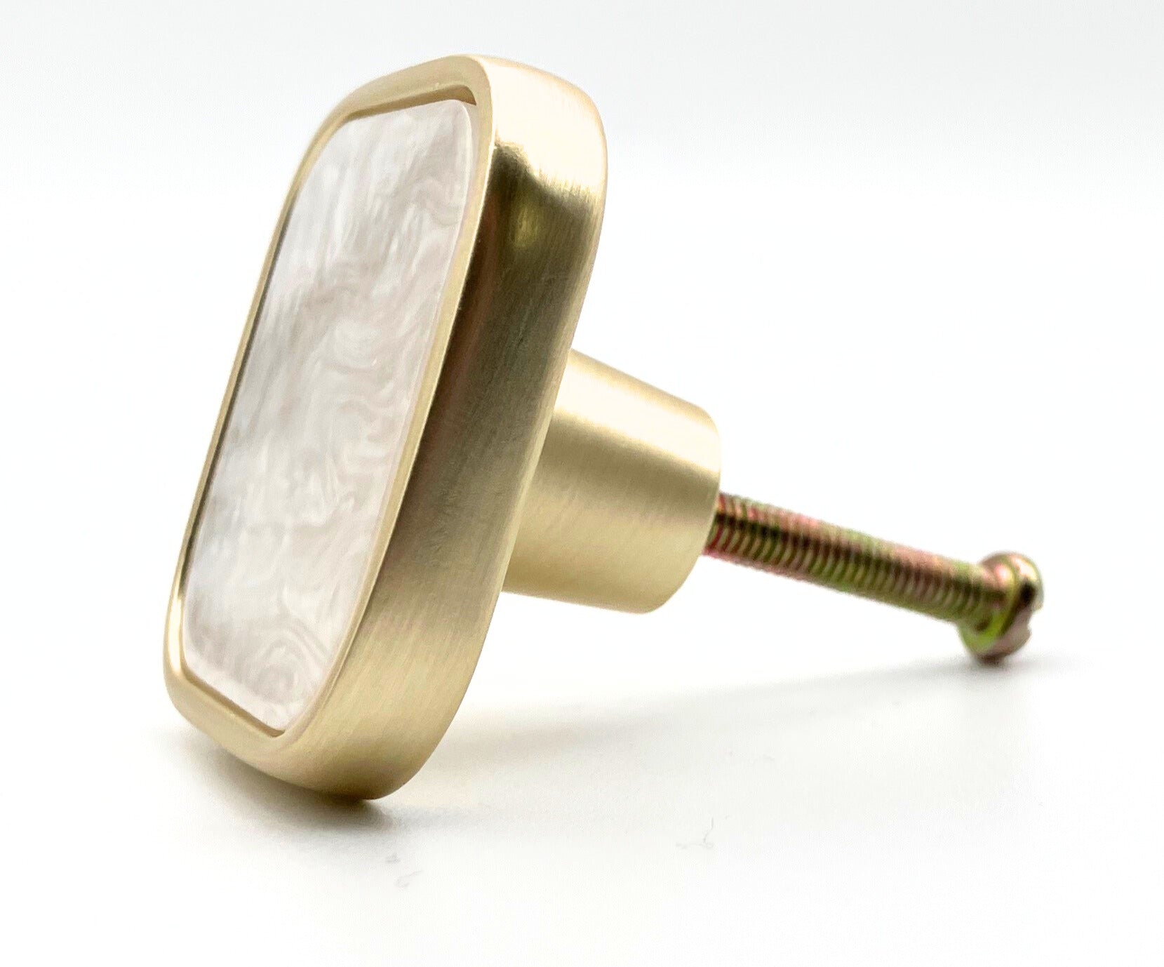 Brass cabinet knob with a white marble center on a white background