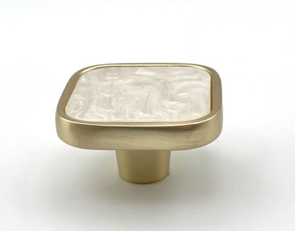 Brass cabinet knob with a white marble texture on a white background