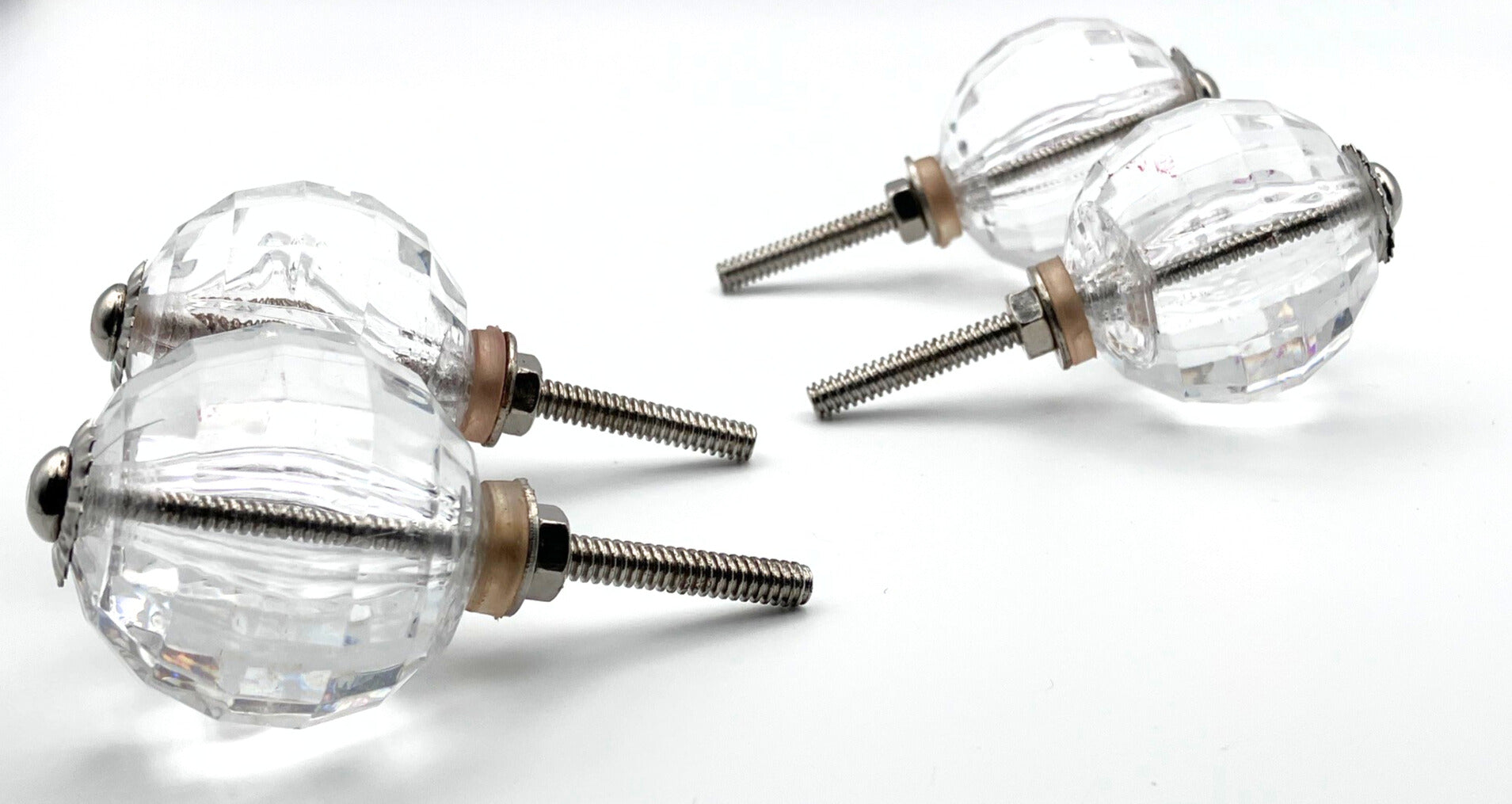 Clear glass knobs with metal stems on a white background