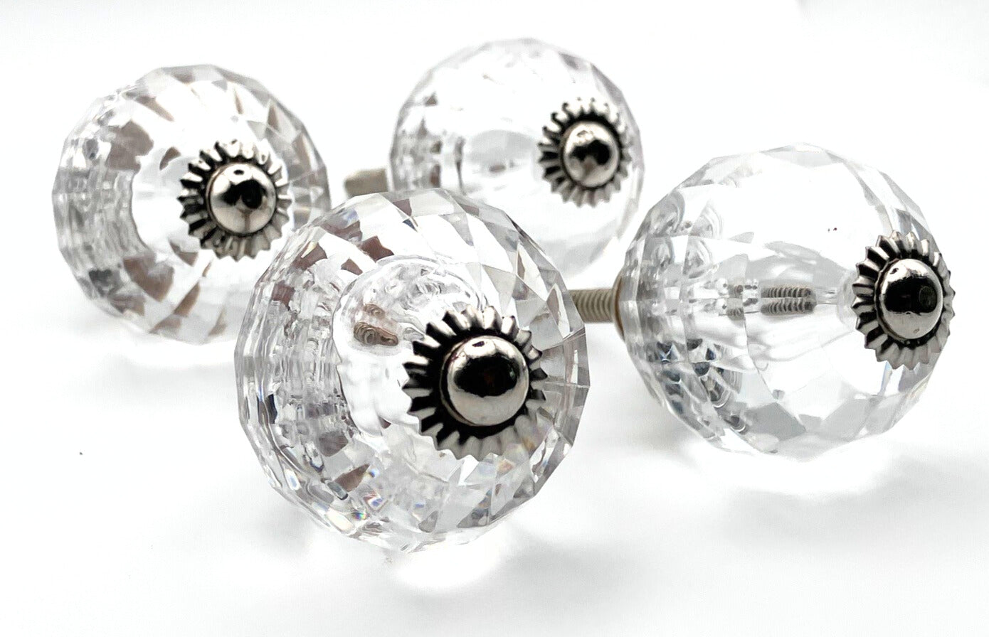 Clear glass knobs with silver central screws on a white background