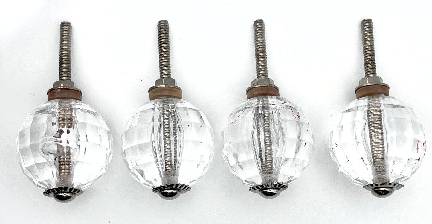 Four clear glass knobs with metal stems on a white background