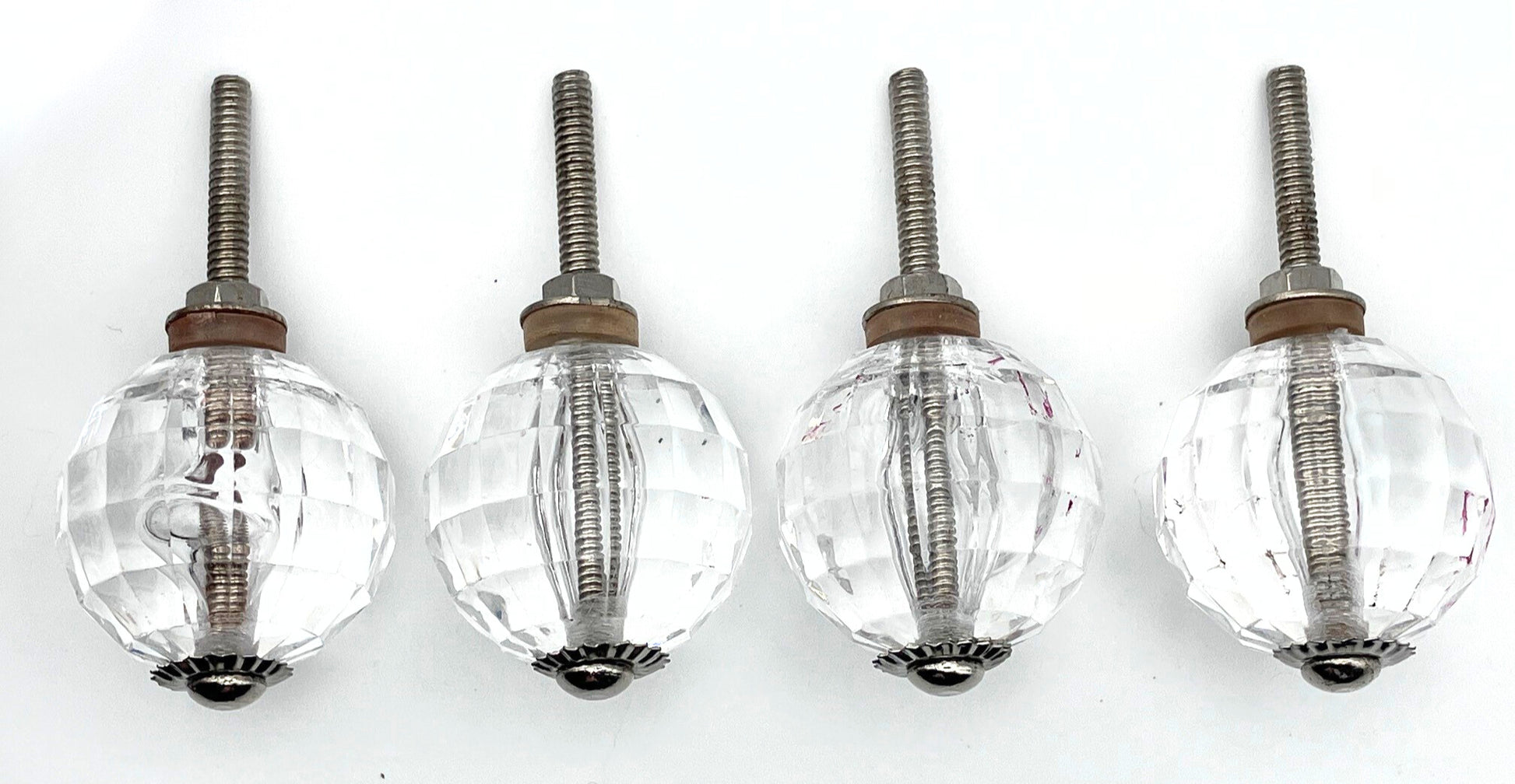 Four clear glass knobs with metal stems on a white background