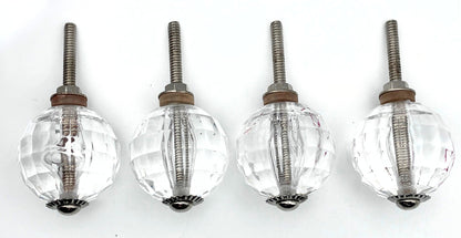 Four clear glass knobs with metal stems on a white background
