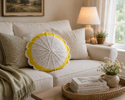 Handmade white crochet pillow with yellow trim displayed on a neutral sofa in a bright cottage living room.