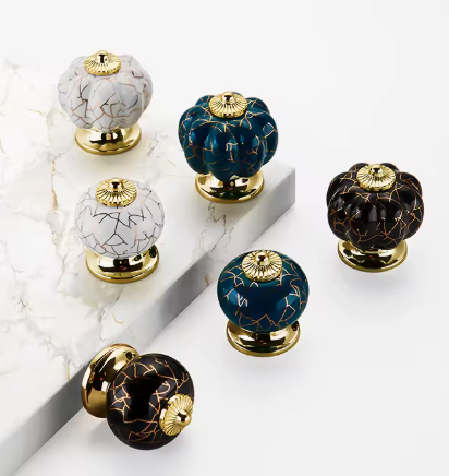 Decorative cabinet knobs with gold accents on a marble surface