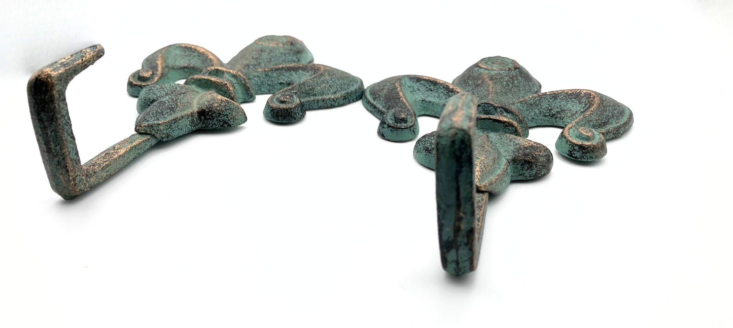 Pair of bronze hooks with a green patina on a white background