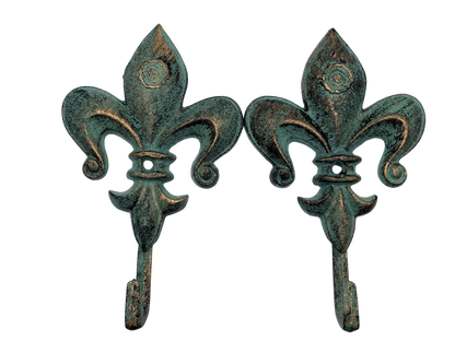 Two fleur-de-lis hooks with a verdigris finish on a white background
