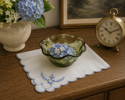 White embroidered floral linen centerpiece styled on a traditional tea table with vintage olive green vintage glass bowl showcased as decorative art glass in a contemporary home setting.