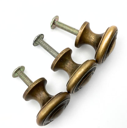 Three brass cabinet knobs with screws on a white background