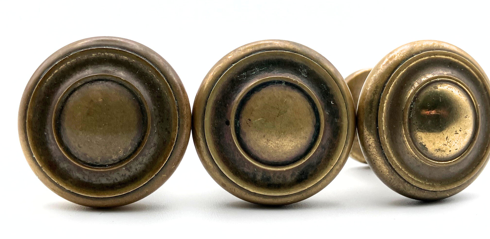 Three brass cabinet knobs on a white background