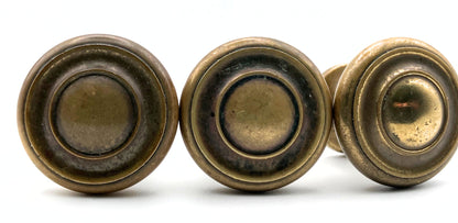 Three brass cabinet knobs on a white background