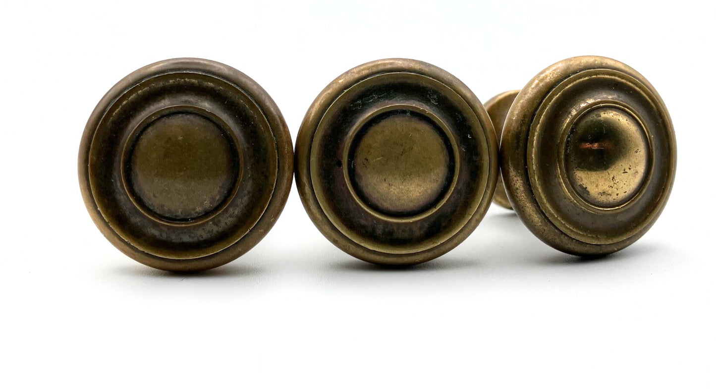 Three bronze-colored circular knobs on a white background