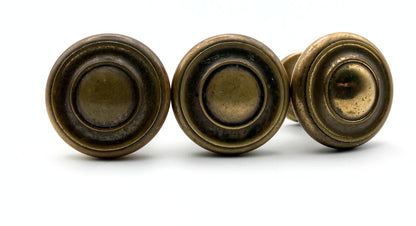 Three bronze-colored circular knobs on a white background