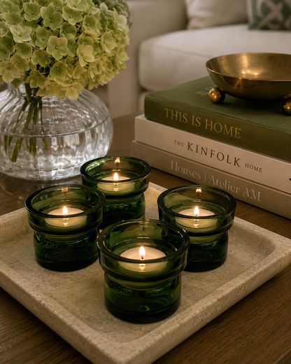 Set of four vintage dark green Dansk glass candle holders styled on a dining table with modern greenery and natural light.