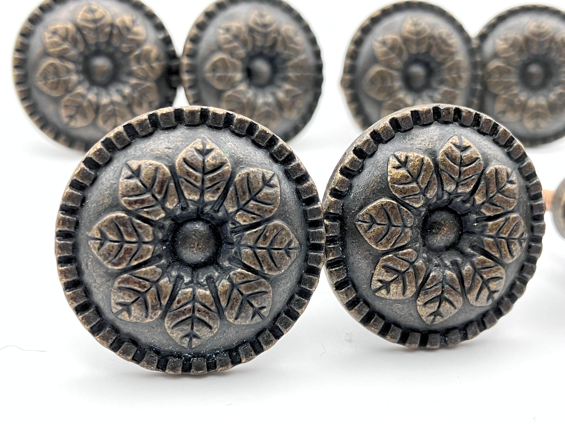 Decorative metal buttons with floral patterns on a white background