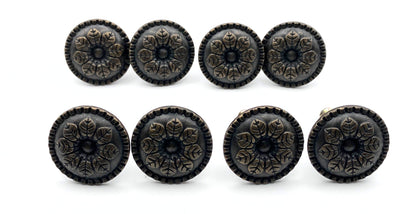 Set of eight decorative black knobs with floral patterns on a white background
