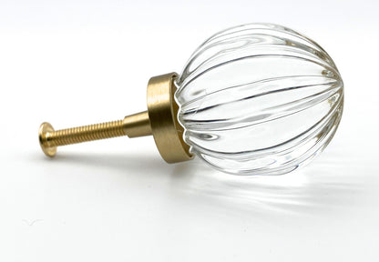 Clear glass knob with gold metal base on a white background