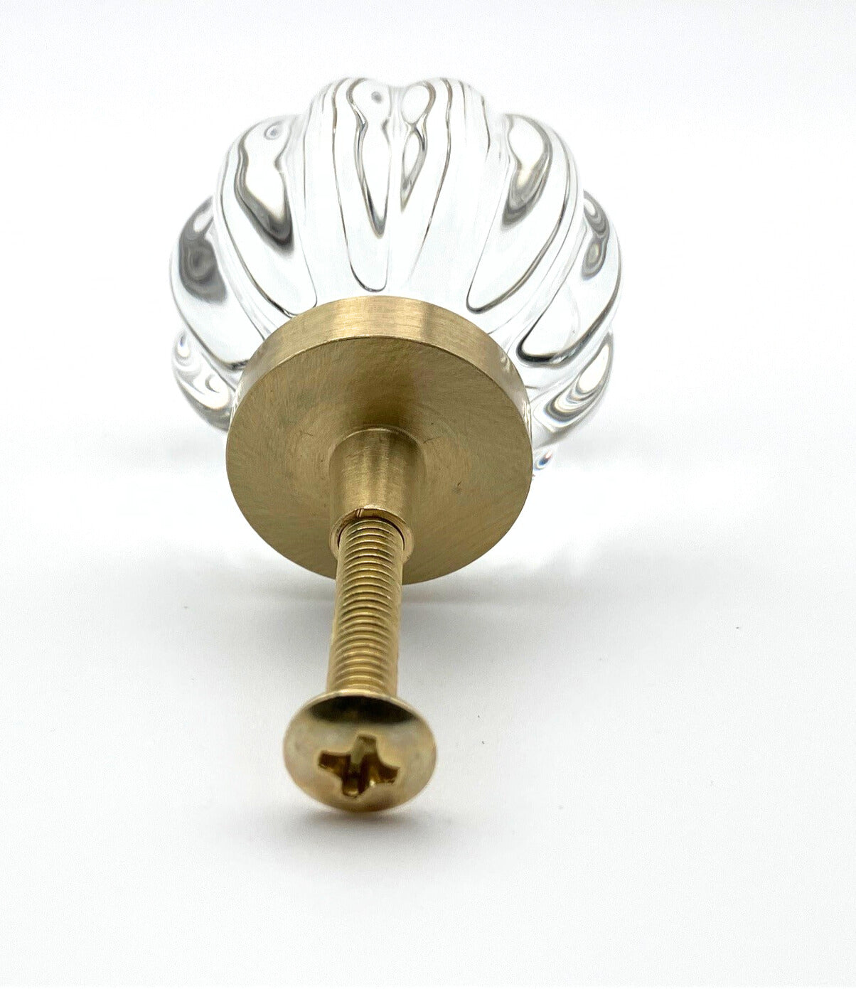 Clear glass ball with ribbed design and gold base on a white background