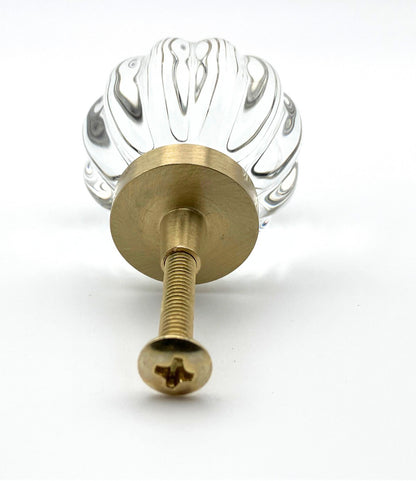 Clear glass ball with ribbed design and gold base on a white background