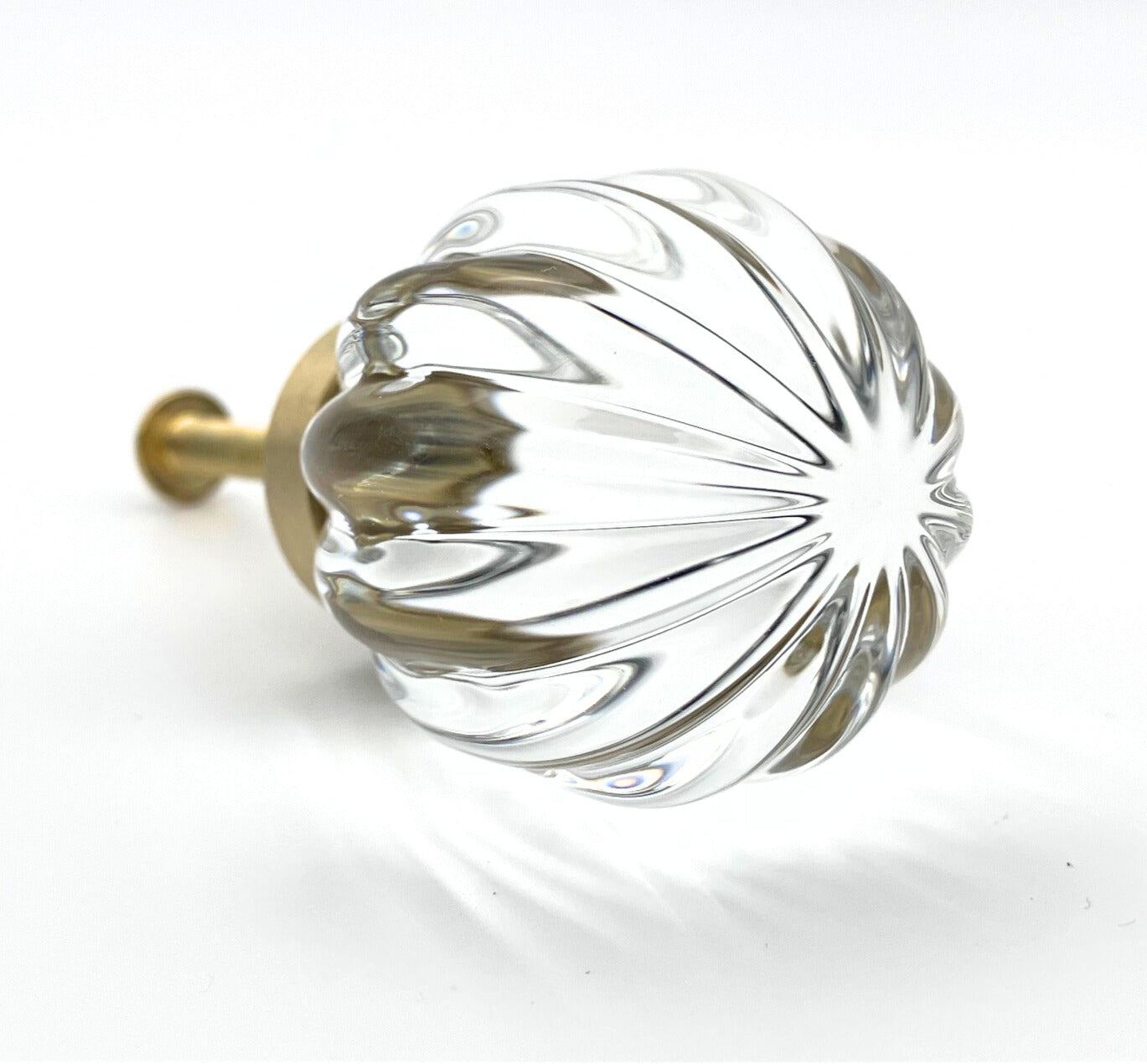 Clear glass ball with ribbed design and gold base on a white background