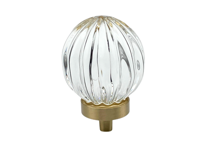 Clear glass ball with ribbed design and gold base on a white background