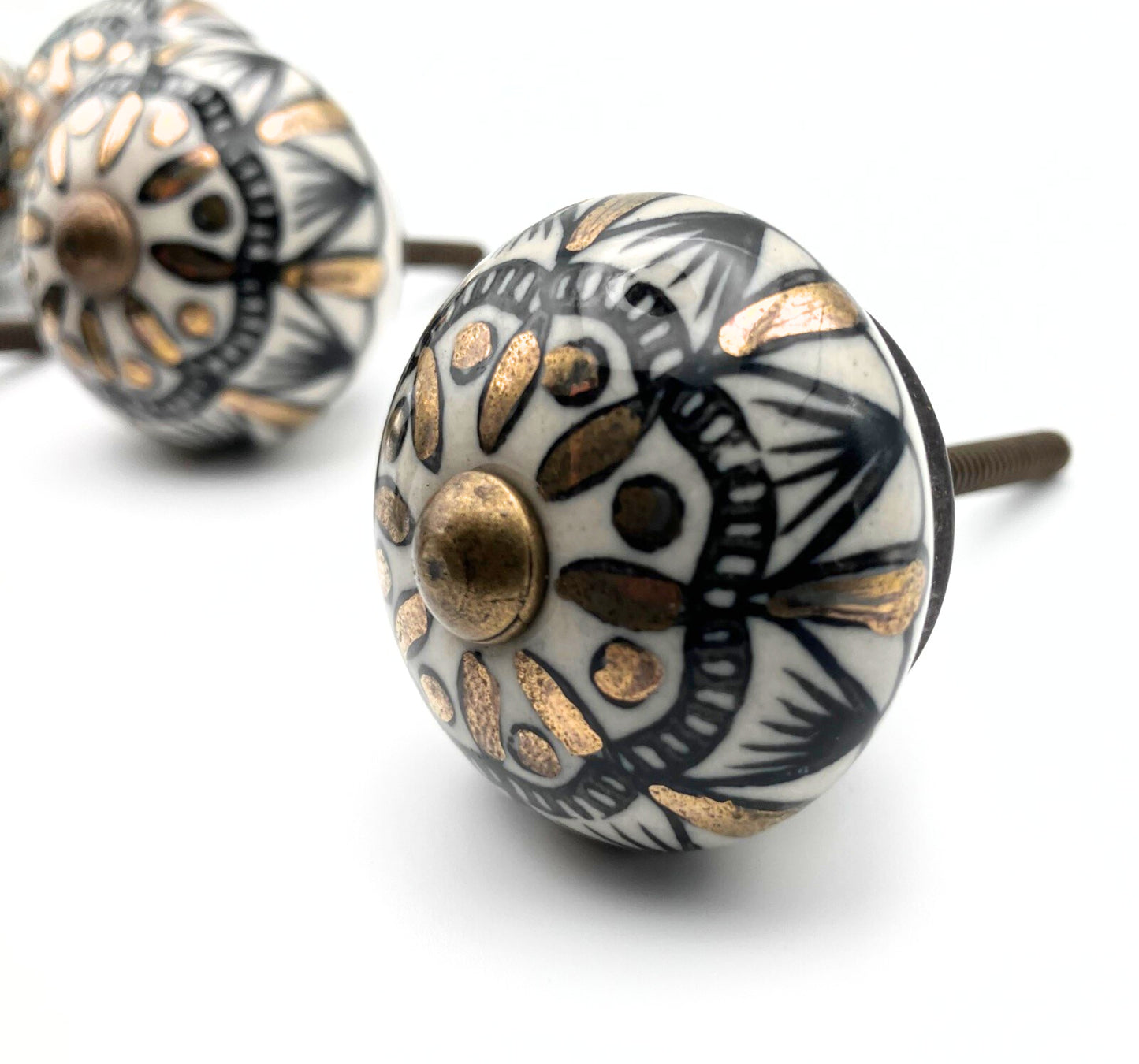 Decorative ceramic knobs with black, white, and gold patterns on a white background