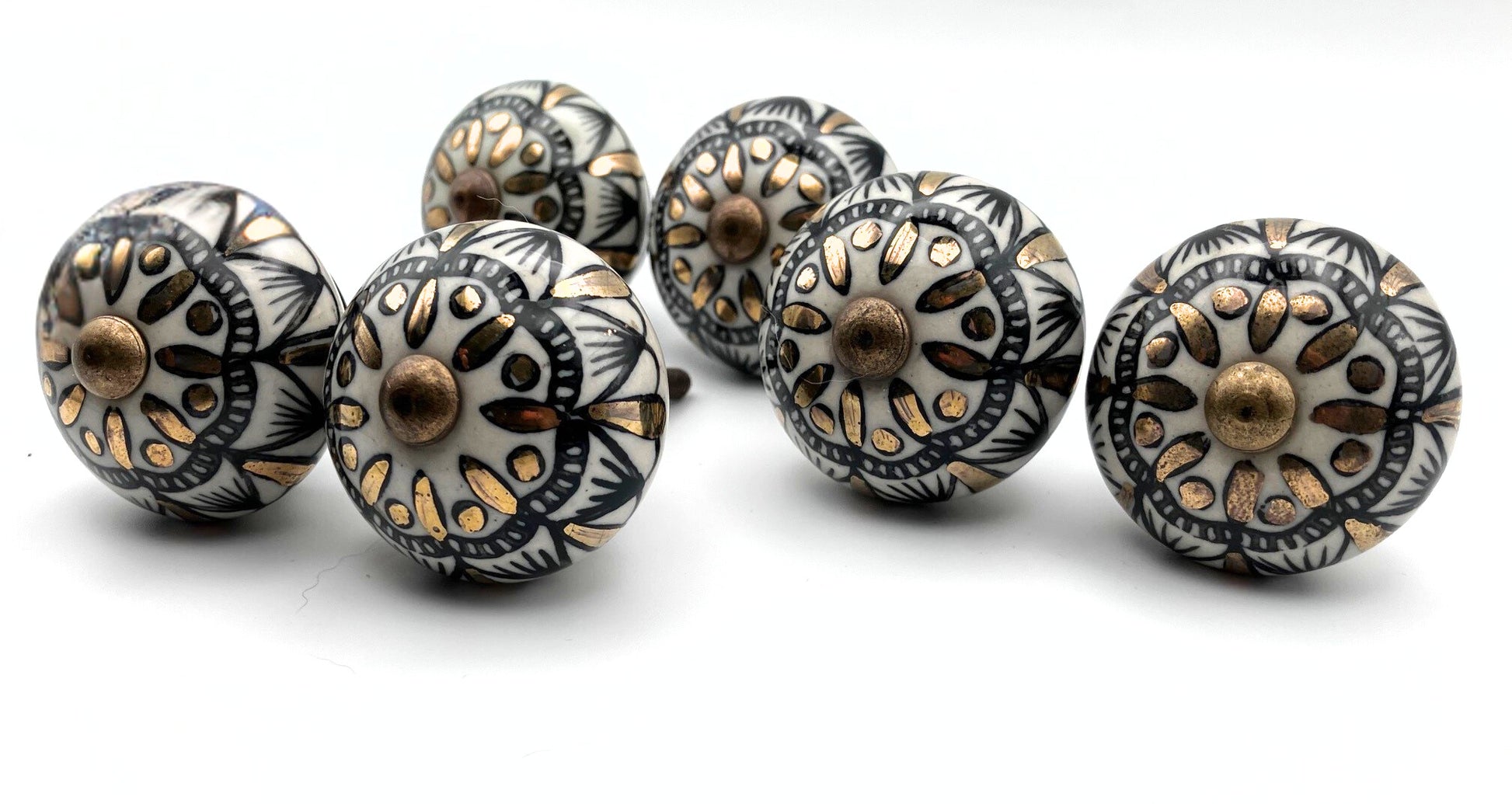 Set of decorative ceramic knobs with black and gold patterns on a white background