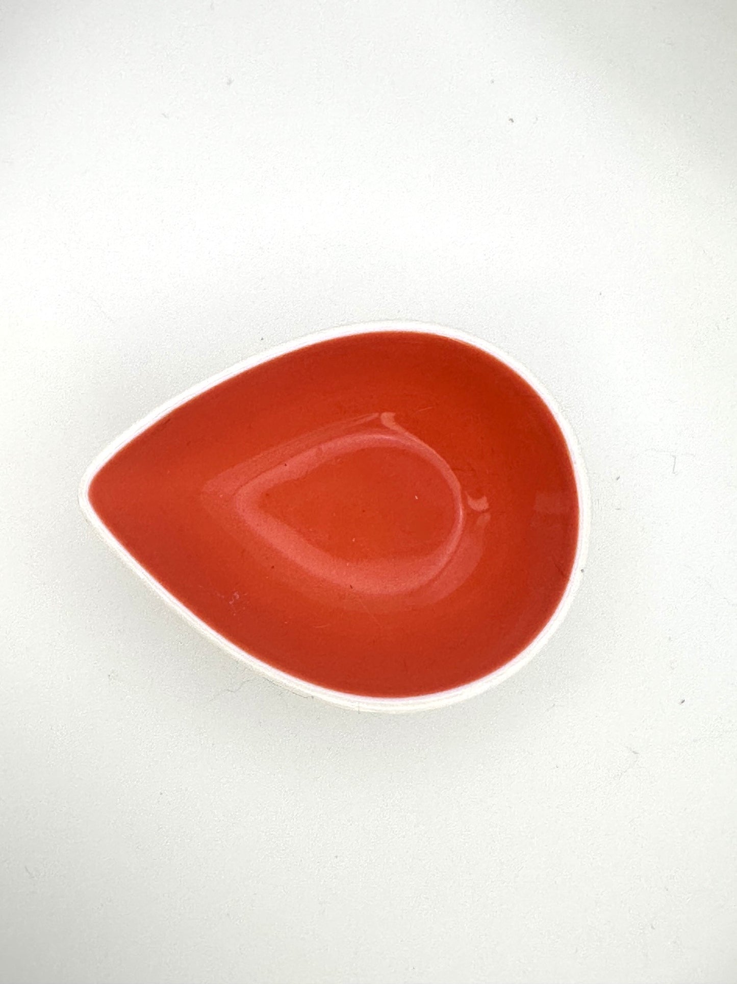 Small ceramic accent bowl with teardrop silhouette and bright orange glazed interior