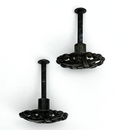 Two black metal knobs with pie-lattice design on white background