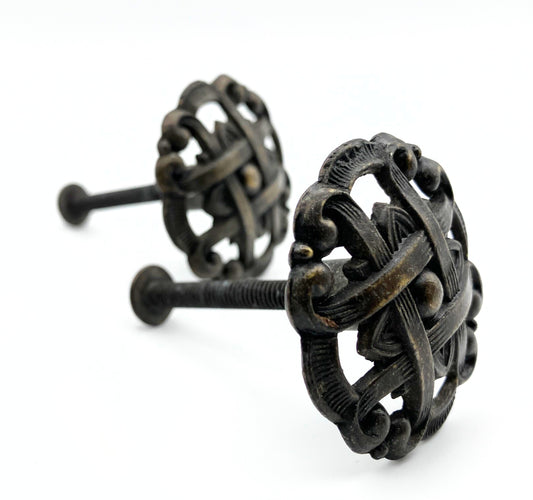 Two black metal knobs with pie-lattice design on white background