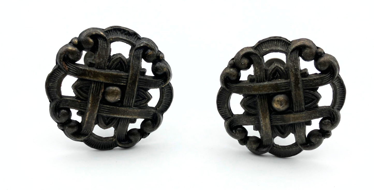 Two black metal knobs with pie-lattice design on white background