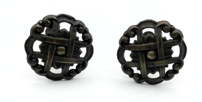 Two black metal knobs with pie-lattice design on white background
