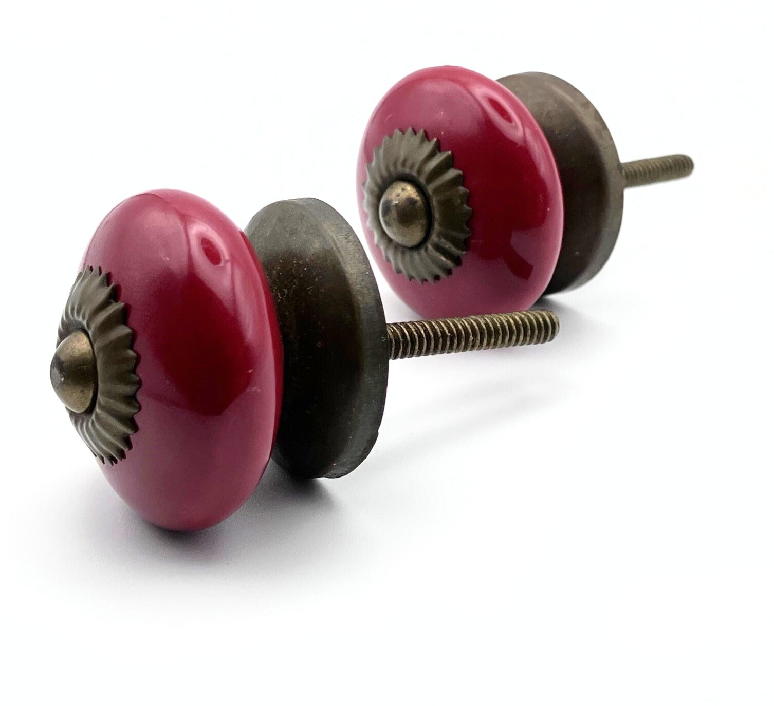 Two red ceramic cabinet knobs with bronze hardware on a white background
