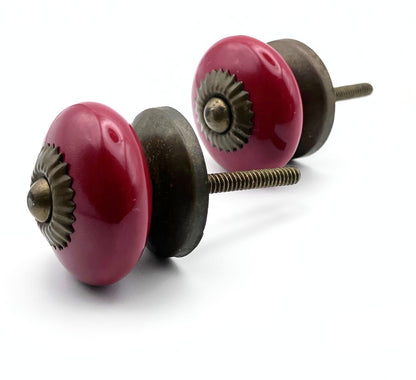 Two red ceramic cabinet knobs with bronze hardware on a white background