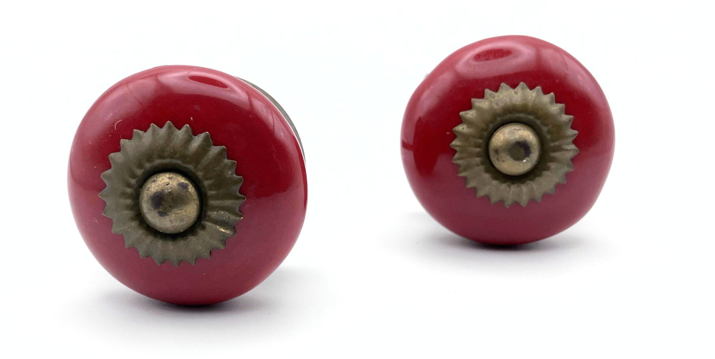 Two red ceramic knobs with metal hardware on a white background