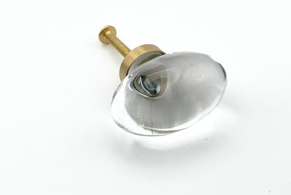 Clear oval glass knob with gold base on a white background