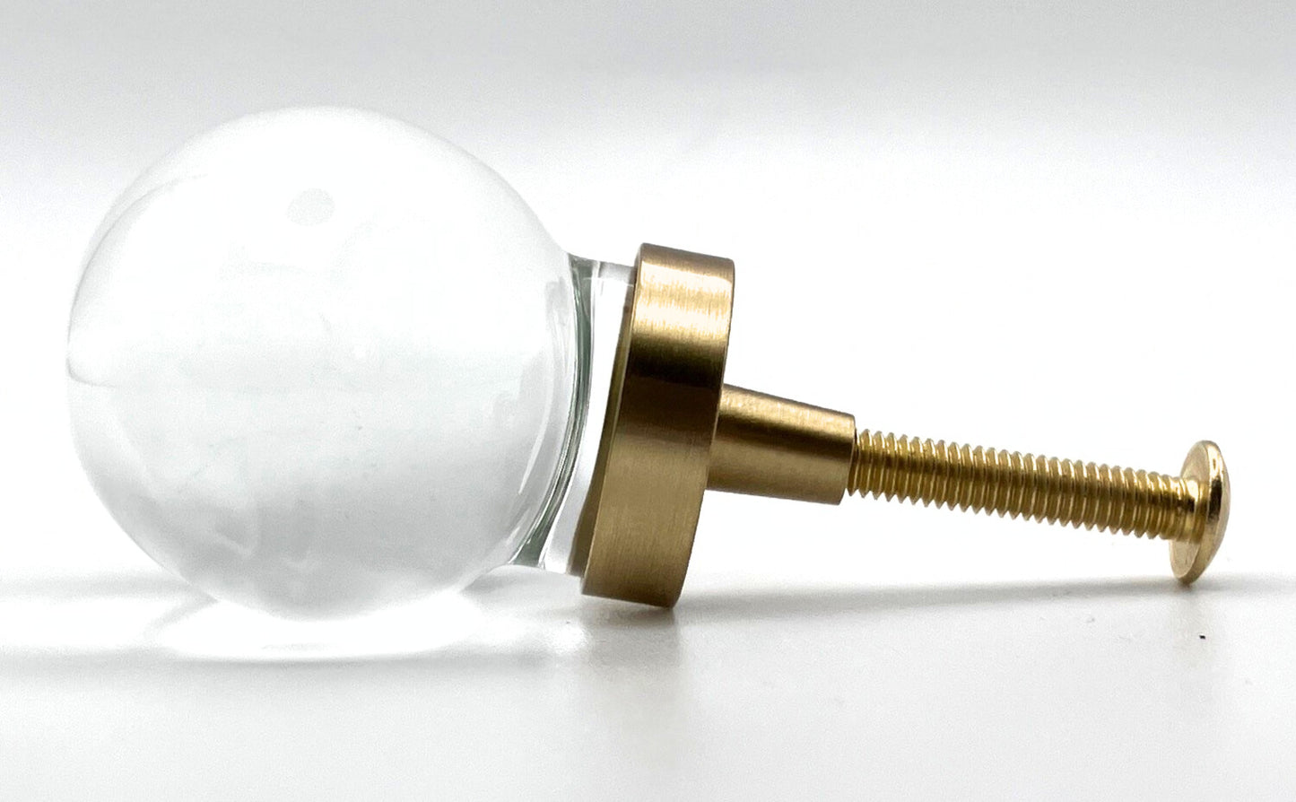 Clear oval glass knob with gold base on a white background