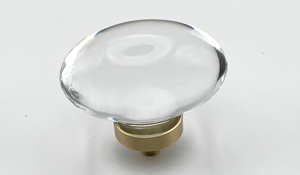 Clear oval glass knob with gold base on a white background