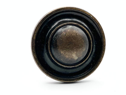 Round black knob with bronze accents on a white background