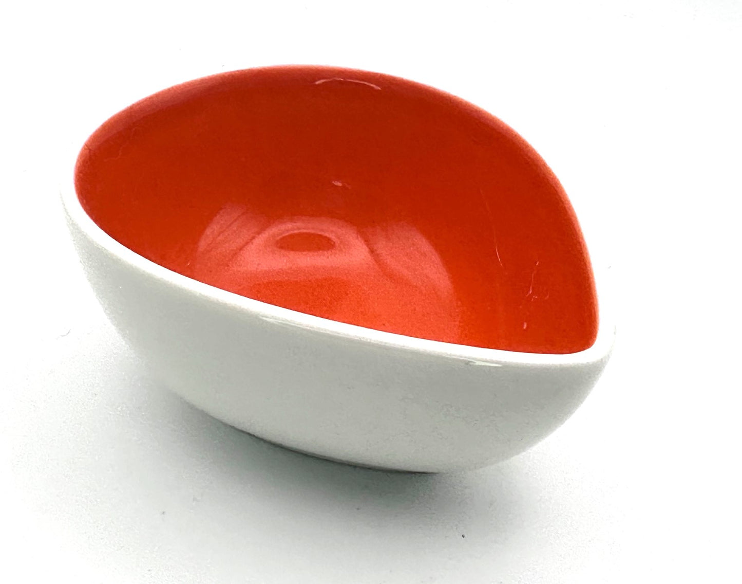 Decorative ceramic teardrop bowl featuring a glossy orange interior and modern styling