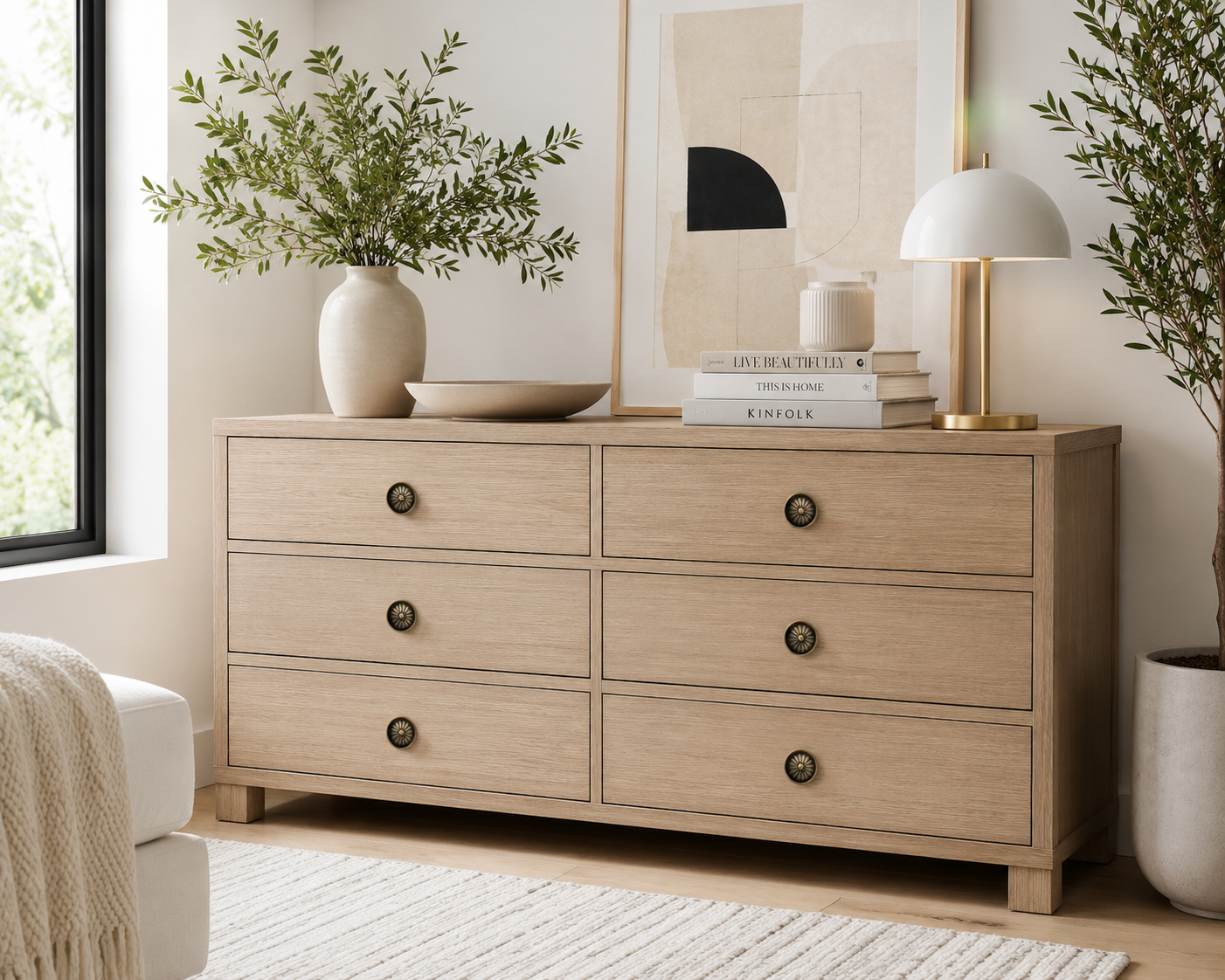 Bronze sunburst cabinet knobs installed on a modern light oak dresser in a bright Scandinavian-inspired room.